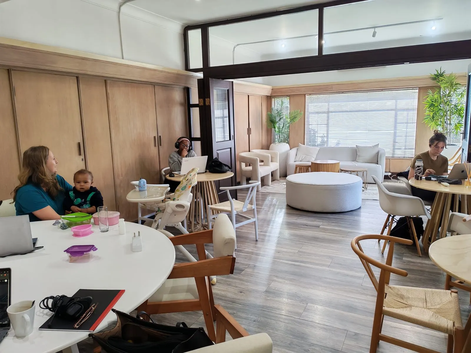 A mother working with her baby on her lap, other mothers at their laptops